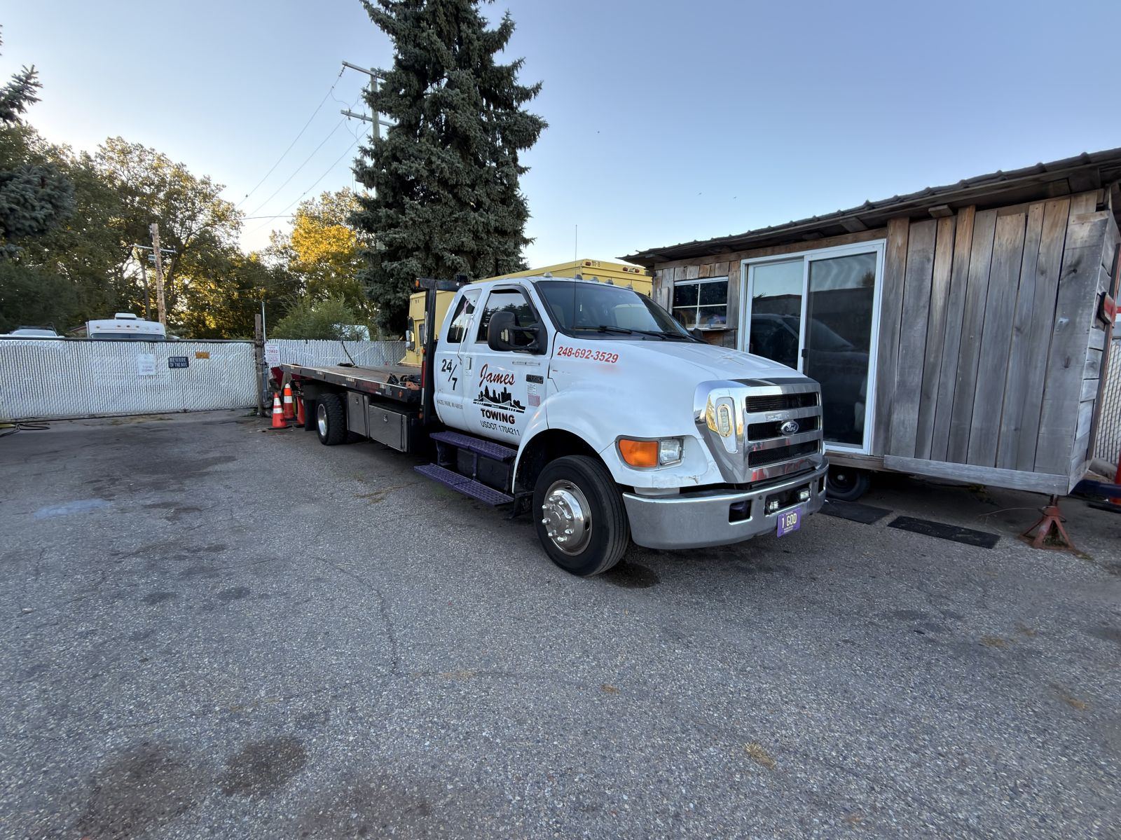 James Towing white Ford F-650 rollback flatbed parked at the yard