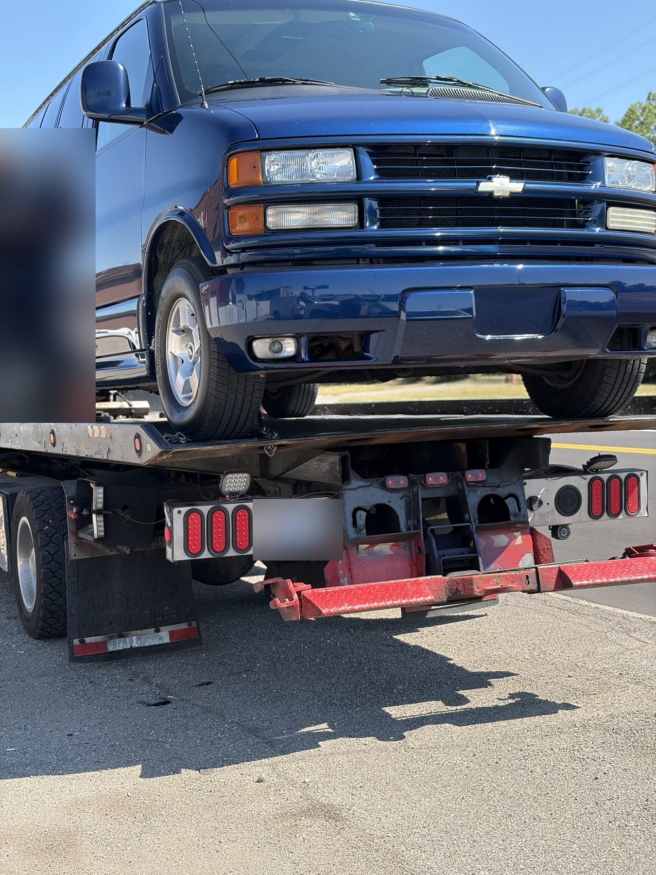 Blue Chevy van secured on a James Towing flatbed